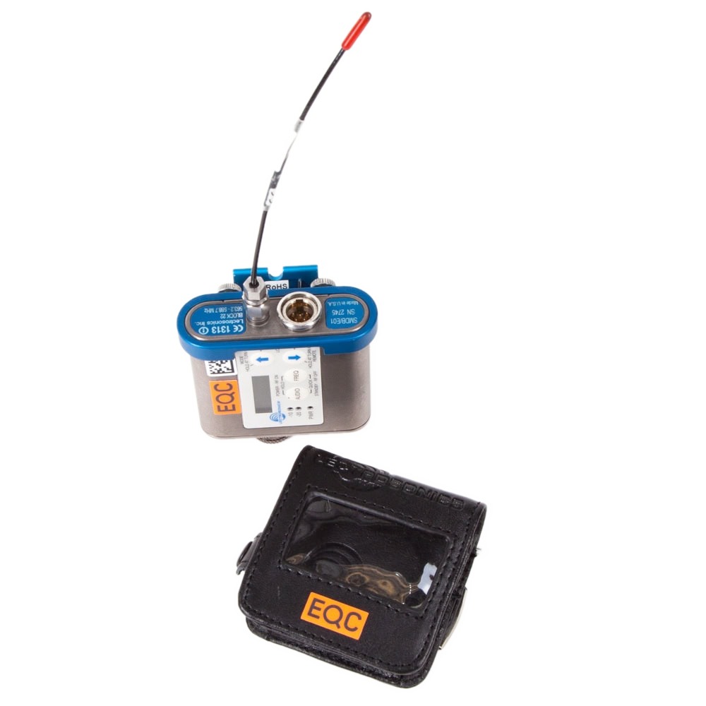 Lectrosonics SMDB Taschensender, Frequenzblock 22, mit Antenne neben zugehöriger Ledertasche.
