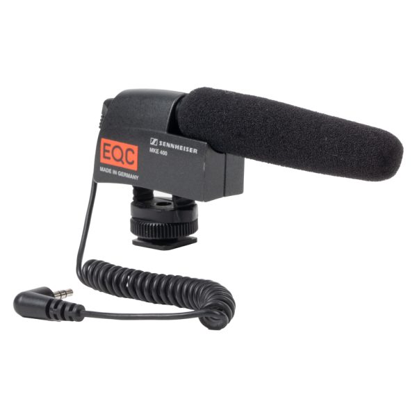 Sennheiser MKE 400 Kameramikrofon mit Schaumstoff-Windschutz, Blitzschuhfuß und Spiralkabel, von der Seite.