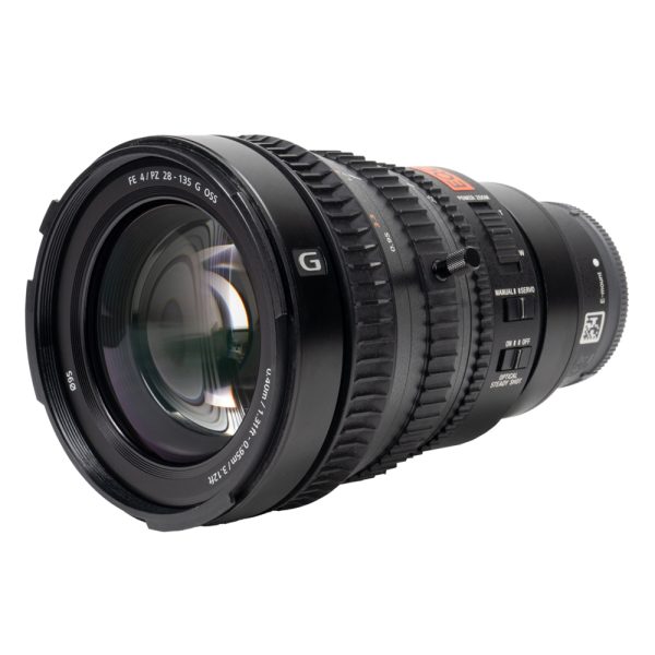 Sony FE PZ 28-135mm f/4 G OSS schräg von vorne mit Frontlinse, Zahnkränzen und Bedienschaltern.